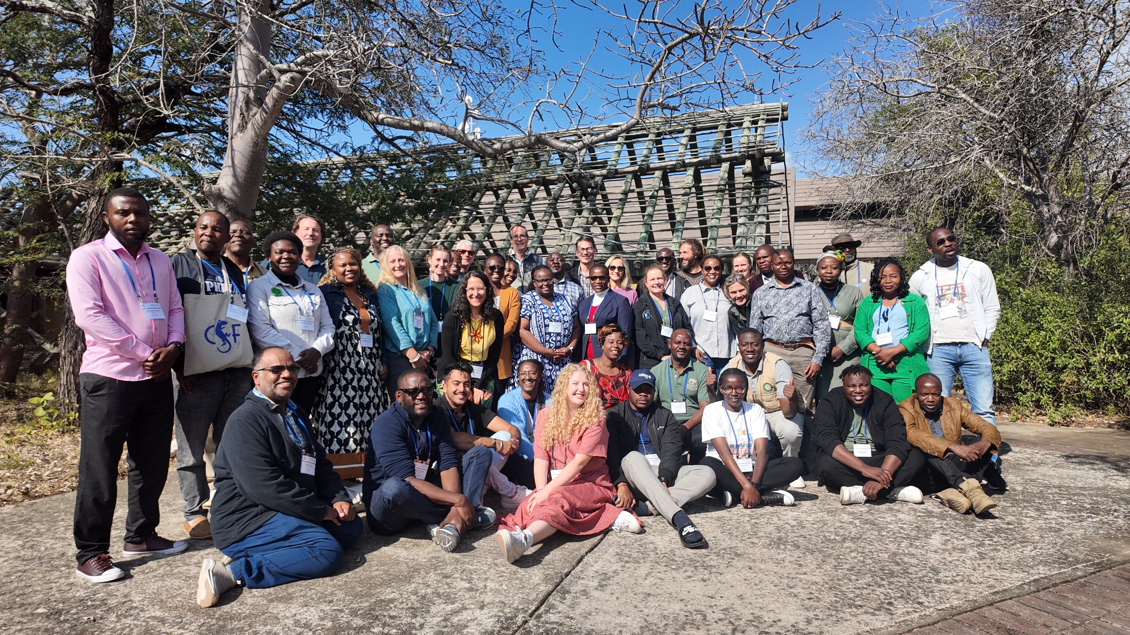 The course cohort is lined up outside and smile for a group photo.