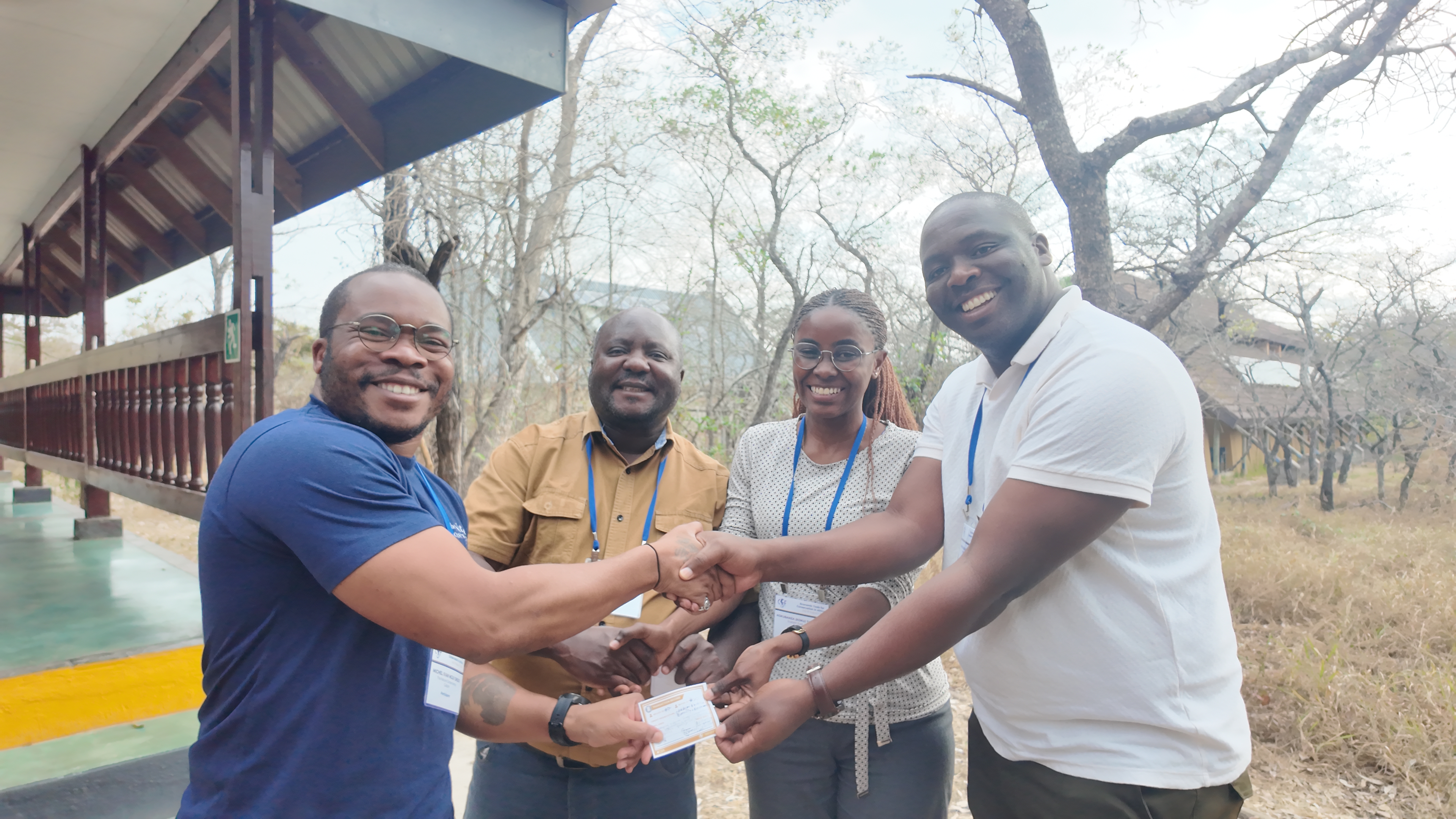 Four participants shake each others hands while smiling.