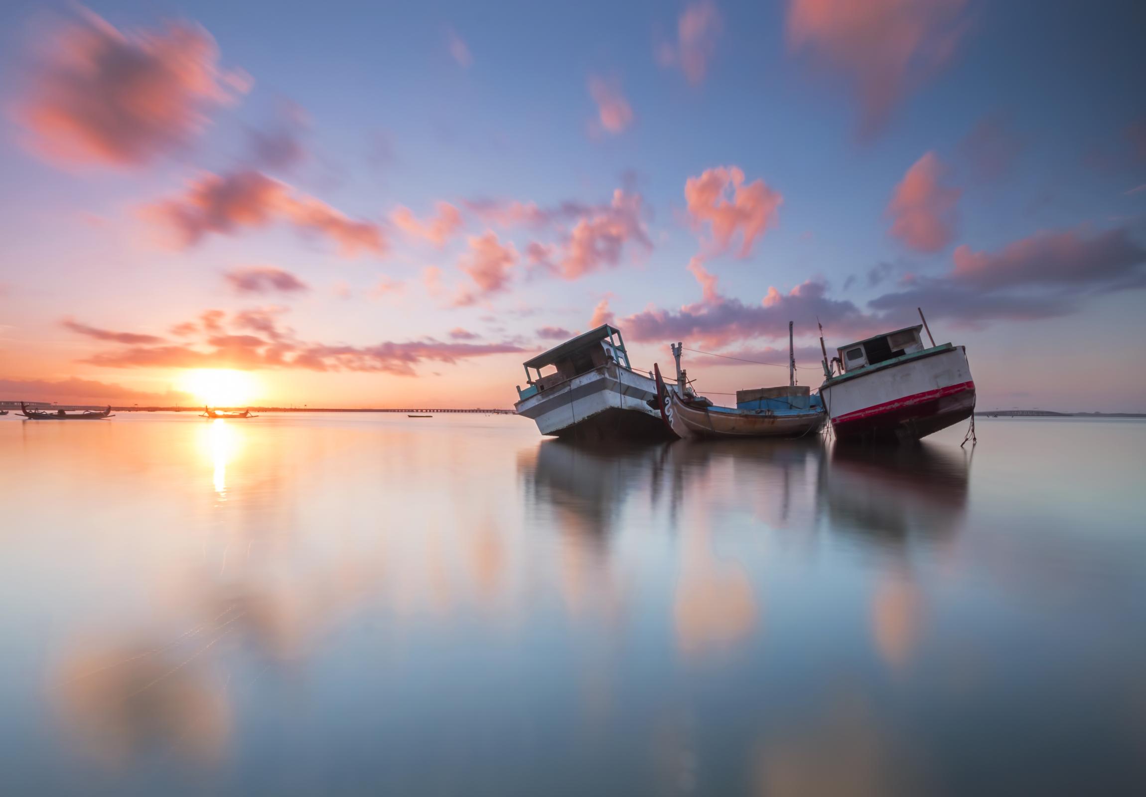 Image of two fishing boats on the water during a sunset