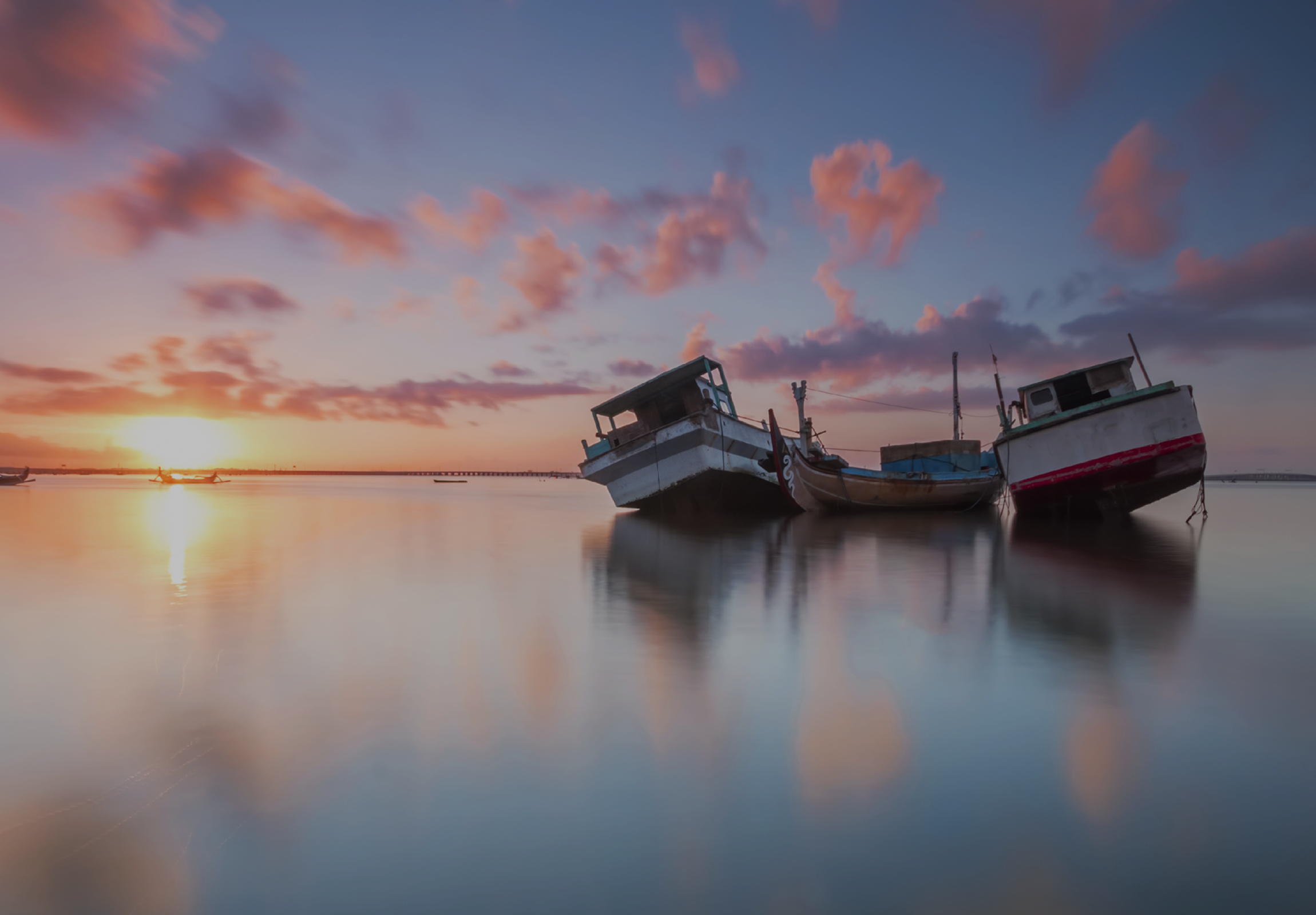 Image of two fishing boats on the water during a sunset